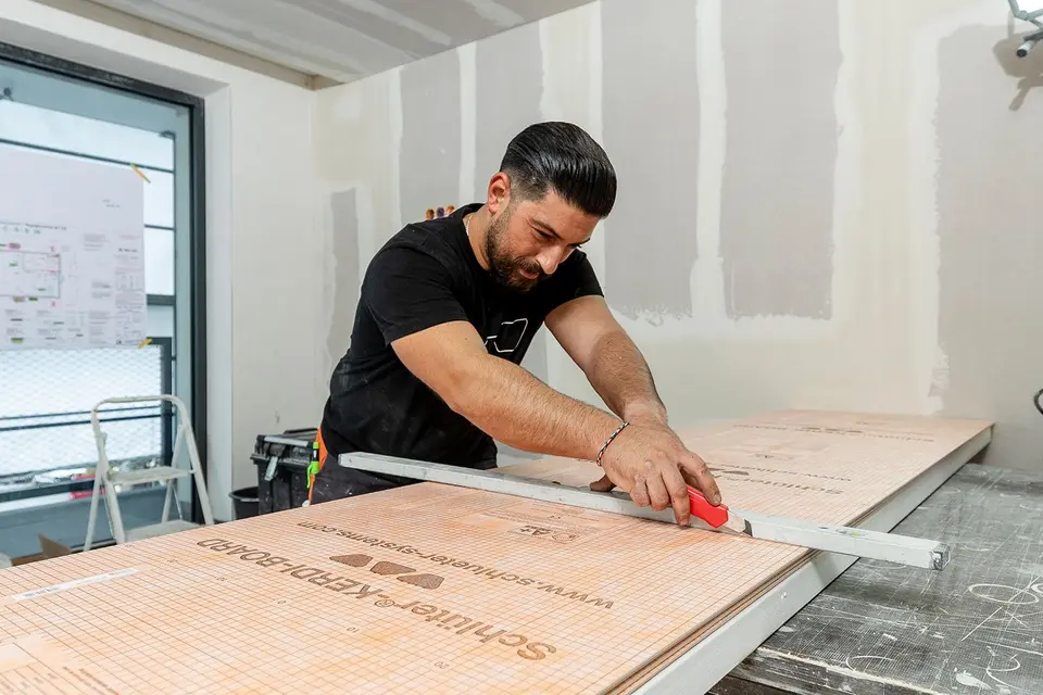 Posatore al lavoro con pannelli Schl&uuml;ter-KERDI-BOARD in cantiere